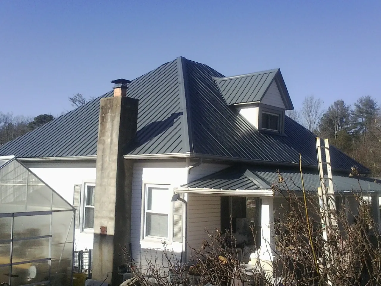 Dark blue standing seam metal roof on a white farmhouse with dormer — Slate & Tile Roof Repair by Roofing Brothers in Smoketown