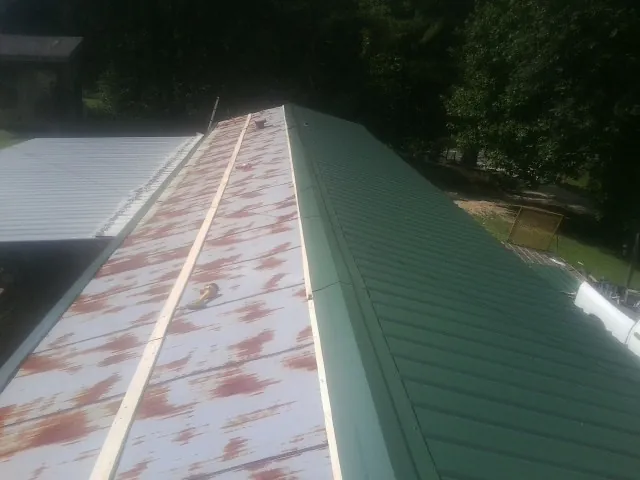 Old rusted panels beside newly installed green metal roofing — Wind Damage Roof Repair by Roofing Brothers in Smoketown