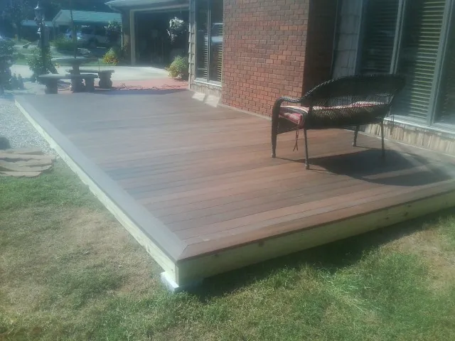 New wood deck and wicker chair beside a brick house in Smoketown