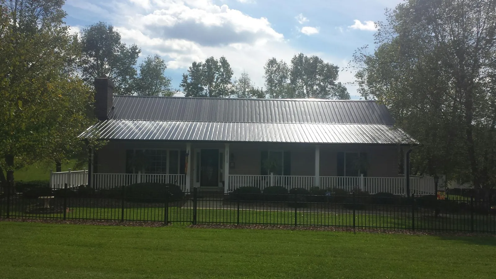 Gray metal roof on a brick ranch with a full width front porch — Gutter Guard Installation work by our crew in Smoketown
