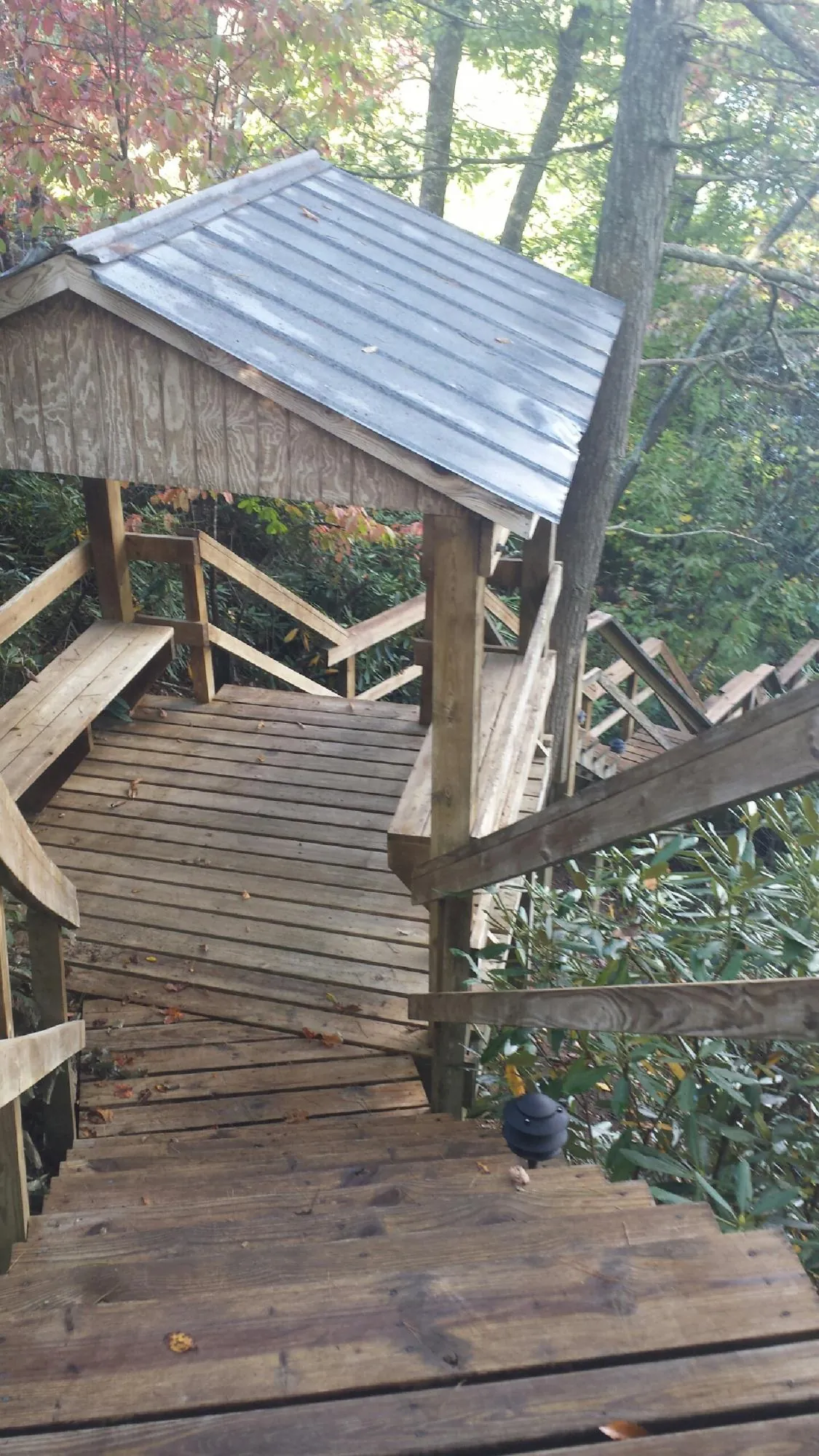 Metal roofed shelter over wooden steps on a wooded walkway — Skylight Repair & Installation work by our crew in Smoketown