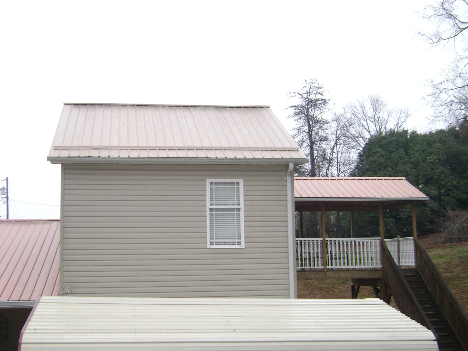 Tan metal roofs on a two story addition and attached porch, from a Roof Replacement job in Smoketown