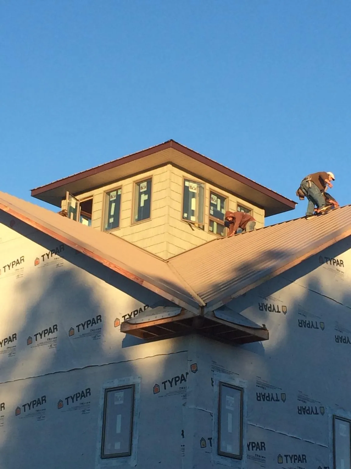 Roofers working around a rooftop cupola on a new metal roof at sunset — Roof Waterproofing in Smoketown by Roofing Brothers